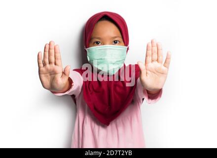 Kleine asiatische muslim hijab Mädchen trägt Maske zeigen Stop Hände Geste Stockfoto