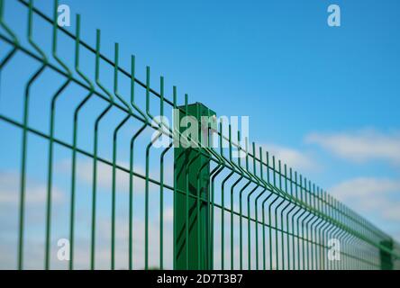 Stahlgitter Zaun mit Draht auf blauem Himmel Hintergrund gemacht. Montage der Abzäunung Stockfoto