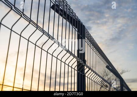 Stahlgitter Zaun mit Draht auf blauem Himmel Hintergrund gemacht. Montage der Abzäunung Stockfoto