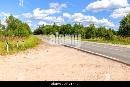 Asphaltstraße in der Landschaft zwischen den Bäumen auf einem Sommer sonnigen Tag Stockfoto