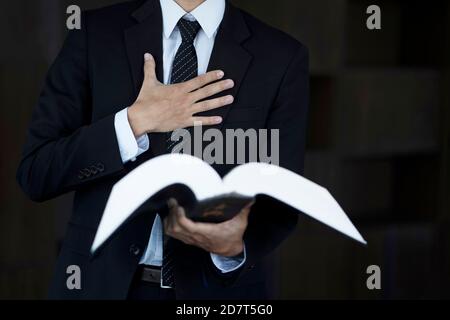 Zugeschnittenes Bild eines Rechtsanwalts, der ein Gesetzbuch hält Stockfoto