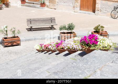 Bunte Blumensträuße auf einer Außentreppe in Cefalù, Sicilia, Italien. Schöne Straßendekoration Stockfoto