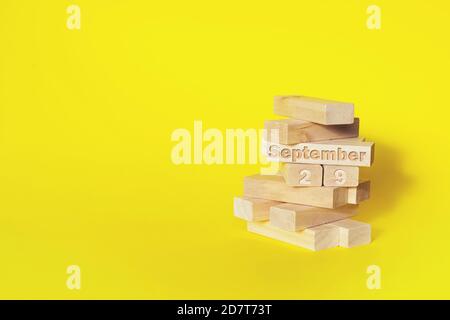 September. Tag 2 9 des Monats, Kalenderdatum. Holzblöcke in den Turm gefaltet mit Monat und Tag auf gelbem Hintergrund, mit Kopieplatz. Herbst m Stockfoto