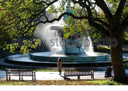 Edinburgh, Schottland, Großbritannien. Oktober 2020. Starke Winde erzeugen viel Spray auf dem normalerweise ruhigen Ross-Brunnen in West Princes Street Gardens, Fußgänger achten darauf, nicht nass zu werden. Durch die Bäume gesehen. Kredit: Craig Brown/Alamy Live Nachrichten Stockfoto