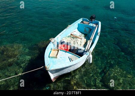 Kleines blaues Boot, das in kristallklarem Wasser in Cefalù, Sizilien, festgemacht ist Stockfoto