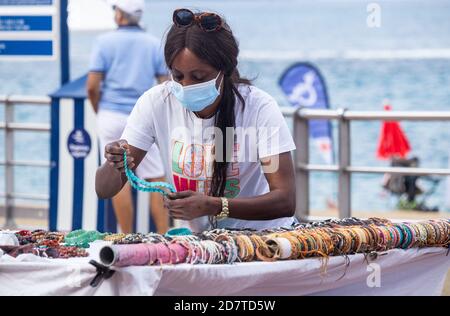 Las Palmas, Gran Canaria, Kanarische Inseln, Spanien. Oktober 2020. Eine Frau stellt ihren Marktstand mit Blick auf den Stadtstrand von Las Palmas auf Gran Canaria auf, während Touristen nach der Nachricht zurückkehren, dass Briten, die von den Kanarischen Inseln zurückkehren, sich nicht mehr selbst isolieren müssen.die spanische Regierung kündigte heute Mittag, Sonntag, 25. Oktober, Dass es einen weiteren bundesweiten Alarmzustand implementiert. Um Covid 19 zu bekämpfen. Wie sich das auf die Kanarischen Inseln auswirken wird, ist noch unklar. Kredit: Alan Dawson/Alamy Live Nachrichten. Stockfoto