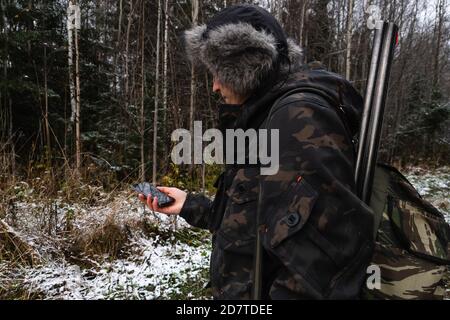 Hunter mit Smartphone in einem Winterwald Stockfoto