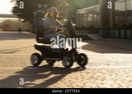 Frau Tourist Reiten ein vier Rad Mobilität Elektroroller auf einer Stadtstraße. Stockfoto