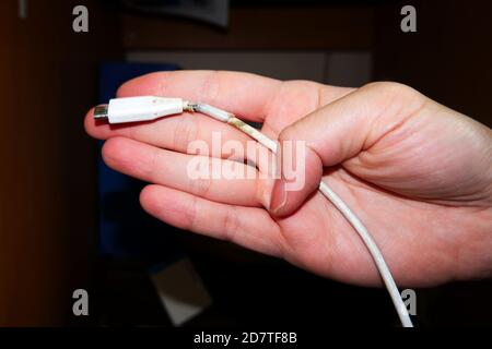 Eine Hand, die ein gebrochenes Kabel vom Typ USB C hält Stockfoto