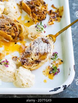 Vertikale Schuss von Apfelstrudel servieren mit Passionsfrucht Quark und Eis Stockfoto