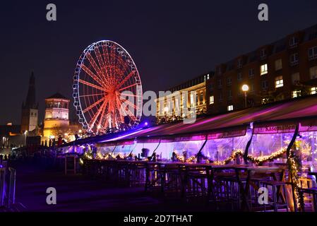 Rheinpromenade mit beleuchtetem Restaurant "Kasematten" im Außenbereich während der Weihnachtszeit. Riesenrad und Burgturm im Hintergrund. Stockfoto