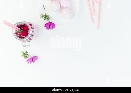 Beeren Smoothie mit Strohhalmen, Marshmallow und Anemonen Blumen auf weißem Hintergrund. Flach liegend. Speicherplatz kopieren Stockfoto