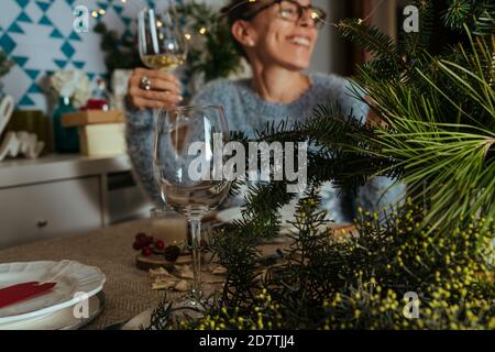 Familie plaudert beim weihnachtsessen, zwei Schwestern sitzen am dekorierten Tisch mit Gläsern Weißwein in der Hand. Familie Zusammen Weihnachtsfest Stockfoto