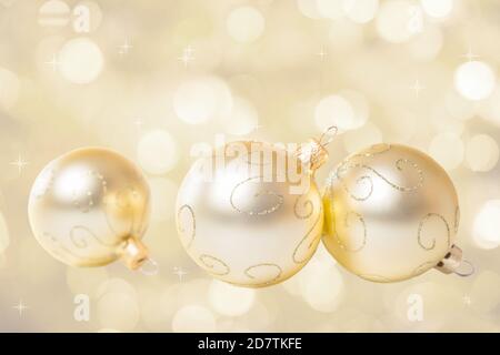 Weihnachtsschmuck. Drei goldene Weihnachtskugeln auf abstraktem Hintergrund Stockfoto