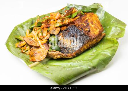 Beliebte gegrillte Stachelrochen Fisch mit Gewürzen und Gemüse serviert Bananenblatt Stockfoto