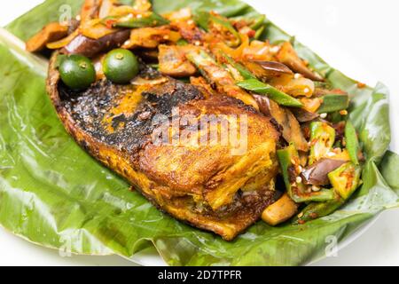 Nahaufnahme des beliebten gegrillten Stachelrochen mit Gewürzen und Gemüse Serviert auf Bananenblatt Stockfoto