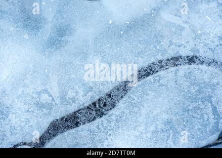 Oberfläche des natürlichen Eises, der im Winter auf dem Wasser bedeckt ist. Eisstruktur mit Zwischenfällen von Frost, Kristallen von gefrorenem Wasser. Stockfoto