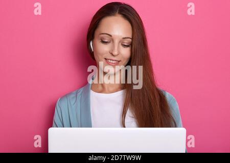 Nahaufnahme Porträt von konzentriert lächelndes Mädchen mit Laptop arbeiten, genießen ihre Arbeit, Blick auf Notizbuch Bildschirm, Dame mit langen dunklen schönen Haaren Stockfoto