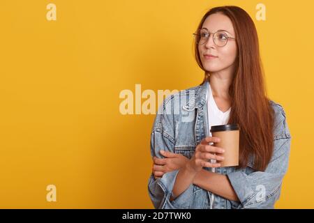 Nahaufnahme Porträt von nachdenklichen Frau mit dunklen Haaren, Blick beiseite, denkt über etwas, trägt weißes T-Shirt, Jeansjacke abd Brillen, Holdi Stockfoto