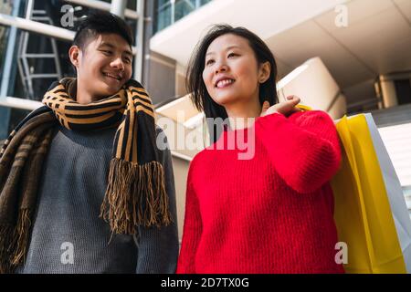 Portrait von schönen asiatischen Paar hält bunte Einkaufstaschen und genießen Shopping, Spaß zusammen in der Mall. Stockfoto