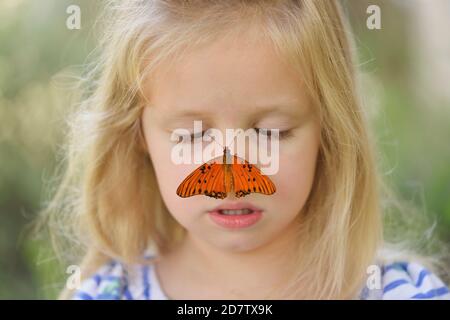 Gulf Fritillary (Agrulis vanillae), Mädchen mit Schmetterling, Hill Country, Central Texas, USA Stockfoto