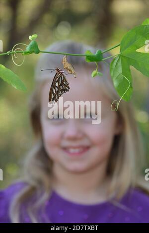 Gulf Fritillary (Agrulis vanillae), Mädchen mit Schmetterling, Hill Country, Central Texas, USA Stockfoto