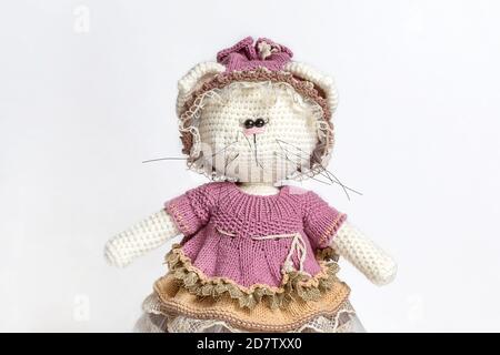 Handgemachtes gestricktes Spielzeug Katze. Gestrickte Katze auf weißem Hintergrund. Porträt eines Spielzeugs. Gestrickte Kleidung für Spielzeug. Nahaufnahme. Amigurumi Katzenspielzeug. Häkeltier Stockfoto