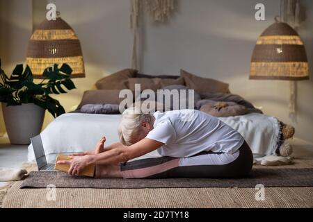 Ältere kaukasische Frau praktiziert Yoga, sitzen in sitzenden vorwärts beugen Übung, paschimottanasana Pose Stockfoto