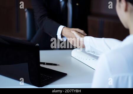 Zugeschnittenes Bild eines Rechtsanwalts, der die Hände beim Kunden schüttelt Stockfoto