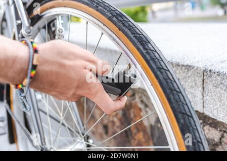 Detail des Lufteinlassventils des Reifens von Ein Fahrrad mit einer angeschlossenen und angeschlossenen Pumpe Die Hände eines jungen Mannes Stockfoto