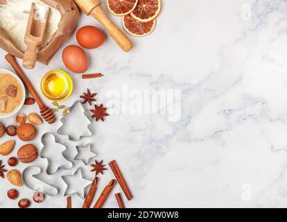 Weihnachten Backen Hintergrund mit Zutaten für die Herstellung von hausgemachten Lebkuchen auf einem Marmor Hintergrund. Fichtenzweige, Spielzeug und Gewürze (cinnamo Stockfoto