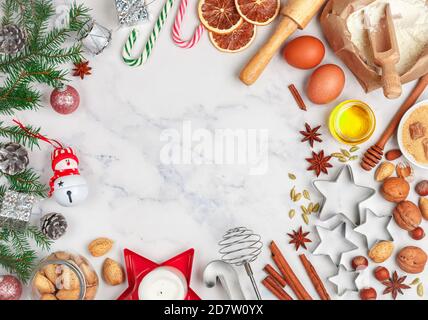 Weihnachten Backen Hintergrund mit Zutaten für die Herstellung von hausgemachten Lebkuchen auf einem Marmor Hintergrund. Fichtenzweige, Spielzeug und Gewürze (cinnamo Stockfoto