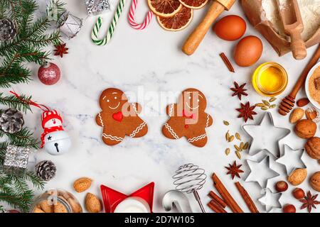 Weihnachten Backen Hintergrund mit Zutaten für die Herstellung von hausgemachten Lebkuchen auf einem Marmor Hintergrund. Fichtenzweige, Spielzeug und Gewürze (cinnamo Stockfoto