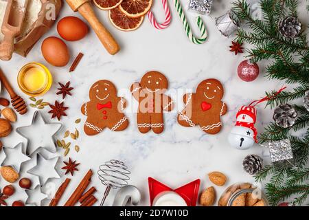Weihnachten Backen Hintergrund mit Zutaten für die Herstellung von hausgemachten Lebkuchen auf einem Marmor Hintergrund. Fichtenzweige, Spielzeug und Gewürze (cinnamo Stockfoto