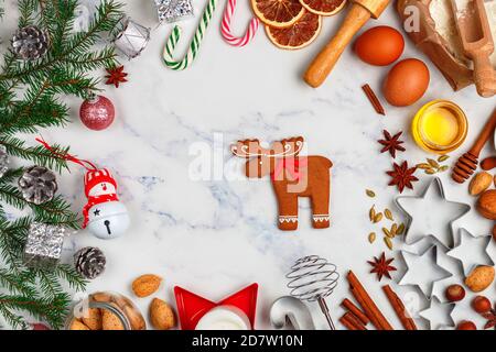 Weihnachten Backen Hintergrund mit Zutaten für die Herstellung von hausgemachten Lebkuchen auf einem Marmor Hintergrund. Fichtenzweige, Spielzeug und Gewürze (cinnamo Stockfoto