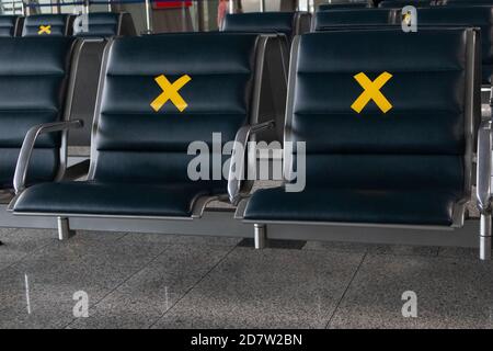 Die Nahaufnahme von Flughafensitzen mit einem Schild ist verboten. Leere Sitzplätze in einer internationalen Flughafenlounge während einer Pandemie. Stockfoto