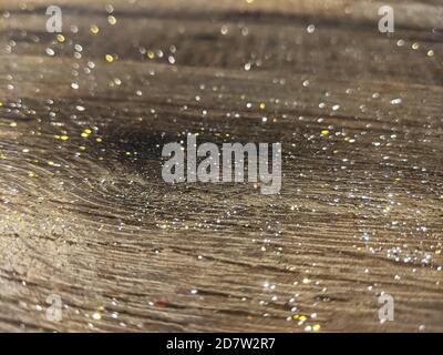 Goldene Partikel glitzern auf dunklem Holzhintergrund Stockfoto