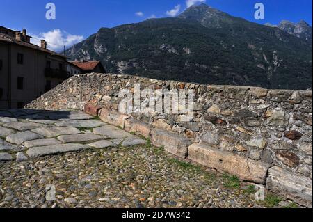 Auf der Ponte Romano, einer eingewölbten Brücke über den Fluss Lys in Pont-Saint-Martin, Valle d'Aosta, Italien, treffen Pflastersteine auf Kopfsteinpflaster. Es wurde vom ersten römischen Kaiser Augustus als Teil der Via delle Gallie, der konsularischen Straße nach Gallie, erbaut. Die Brücke wurde später von mittelalterlichen christlichen Pilgern nach der Via Francigena von Canterbury, England, nach Rom und dann weiter zu den Häfen von Apulien in Italiens äußerstem Süden genutzt. Stockfoto