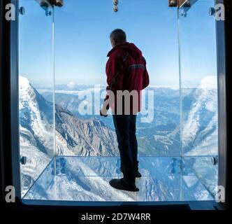 Tourist steht in der Glasbox "Step into the Void" auf dem Gipfel des Aiguille Du Midi (3842m) oberhalb des Mont-Blanc-Massivs von Chamonix, Frankreich. Stockfoto