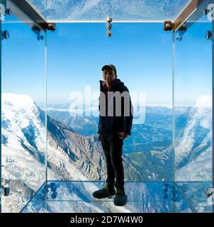 Tourist steht in der Glasbox "Step into the Void" auf dem Gipfel des Aiguille Du Midi (3842m) oberhalb des Mont-Blanc-Massivs von Chamonix, Frankreich. Stockfoto