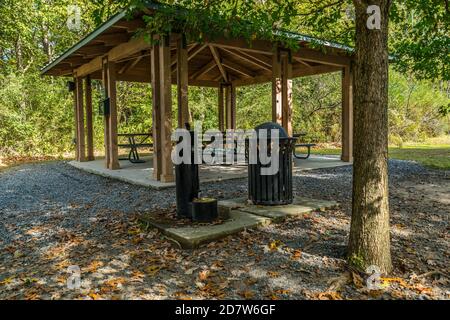 Ein kleiner Picknickpavillon mit mehreren Tischen für Versammlungen Wasserbrunnen mit einer Mülltonne auf Zementpads umgeben Durch die Wälder in einem Park in Stockfoto