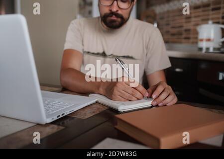 Konzentrierter Millennial Hipster Kerl trägt Brille, hören Lieblingsmusik während der Planung Arbeitstag. Fokussierte junge biracial Geschäftsmann beobachten e Stockfoto