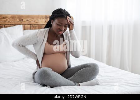 Migräne Während Der Schwangerschaft. Schwarze schwangere Frau leidet unter starken Kopfschmerzen zu Hause Stockfoto