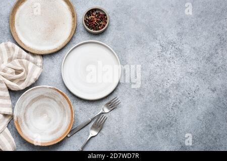 Tischeinstellung mit trendigen grauen Keramikplatten auf grauem Betongrund. Draufsicht Stockfoto