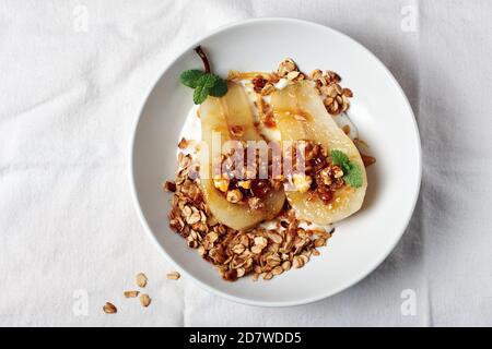 Pochierte Birne mit Joghurt, Walnüssen und Hafergranola. Stockfoto