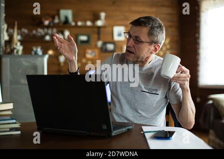 Mittlerer Erwachsener Mann hält Tasse ein Gespräch mit Videokonferenz. Stockfoto