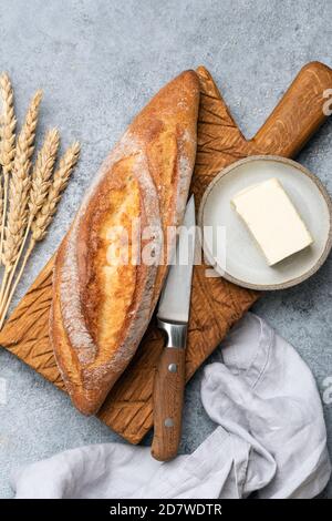 Französisches Baguette-Brot und Butter auf Holzschneidebrett. Draufsicht Stockfoto