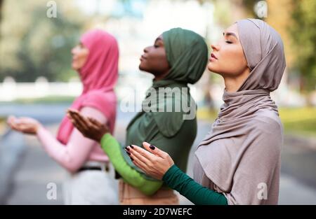 Drei Muslimische Frauen Beten Zusammen Im Freien Stehend Im Traditionellen Hijab Stockfoto