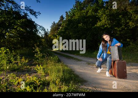 Ein Teenager wartet auf ein Auto, das sie zu ihrer Familie nach Hause bringt. Ende des Sommers Abenteuer. Stockfoto
