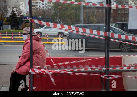 Moskau, Russland. 25. Oktober 2020 eine ältere Frau mit Gesichtsmaske sitzt an einer Bushaltestelle in der Nähe der U-Bahnstation Sokolniki im Zentrum von Moskau, Russland. Vom 9. Bis 28. Oktober suspendierten die Moskauer Behörden wegen der neuartigen Coronavirus-Pandemie COVID-19 in Russland die Freikarte für die öffentlichen Verkehrsmittel für Moskauer über 65 Jahre und Menschen mit chronischen Krankheiten Stockfoto